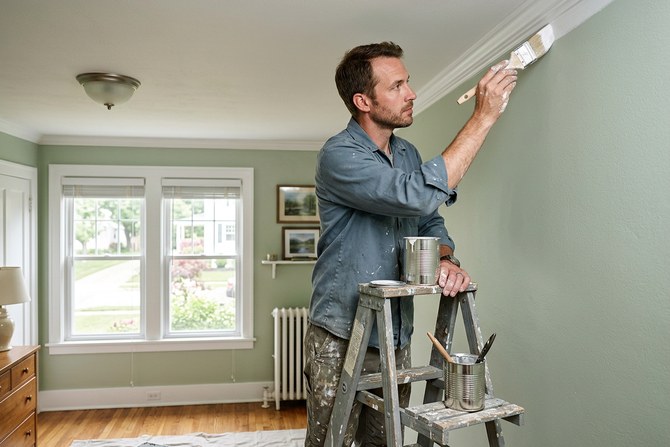 Painter cutting in trim with a brush in a freshly painted room